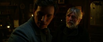 Movie still from “The Aeronauts” (2019), directed by Tom Harper – A man standing next to another man in a dark room; Close Up shot, Over the shoulder angle