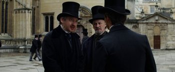 Movie still from “The Aeronauts” (2019), directed by Tom Harper – A group of men in top hats and coats; Medium shot, Over the shoulder angle
