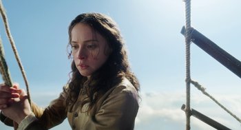 Movie still from “The Aeronauts” (2019), directed by Tom Harper – A woman with long brown curly hair standing in front of the sky; Close Up shot, Low angle