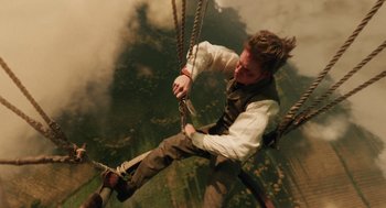 Movie still from “The Aeronauts” (2019), directed by Tom Harper – A man is hanging from a rope swing; Medium shot, Low angle