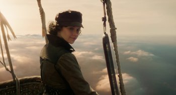 Movie still from “The Aeronauts” (2019), directed by Tom Harper – A woman with glasses and a hat is standing on a swing; Medium shot, Low angle
