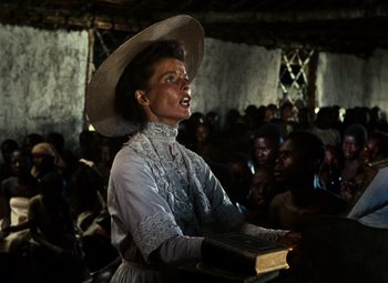 Movie still from “The African Queen” (1951), directed by John Huston – A woman in a hat is holding a book; Medium shot, Low angle
