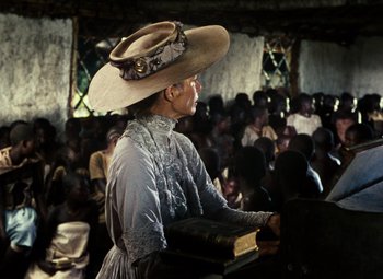 Movie still from “The African Queen” (1951), directed by John Huston – An older woman in a hat is holding a book; Medium shot, Low angle