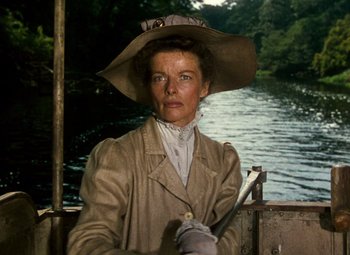 Movie still from “The African Queen” (1951), directed by John Huston – An older woman wearing a hat while standing on a boat; Close Up shot, Low angle