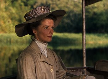 Movie still from “The African Queen” (1951), directed by John Huston – A woman wearing a hat is standing in front of a body of water; Close Up shot, Low angle
