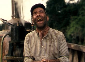 Movie still from “The African Queen” (1951), directed by John Huston – An old man with a beard and a hat is laughing; Medium shot, Low angle
