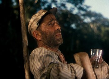 Movie still from “The African Queen” (1951), directed by John Huston – A man with a beard and a hat is holding a glass of wine; Close Up shot, Low angle