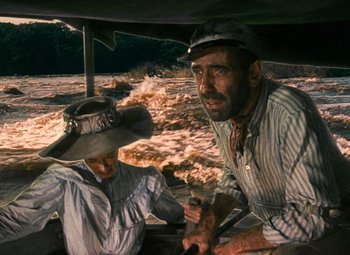 Movie still from “The African Queen” (1951), directed by John Huston – A man and a woman sitting on a boat in the water; Medium shot, High angle
