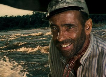 Movie still from “The African Queen” (1951), directed by John Huston – A man with a hat is smiling for the camera; Close Up shot, Over the shoulder angle