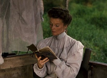 Movie still from “The African Queen” (1951), directed by John Huston – An old woman reading an old book outside; Medium shot, High angle