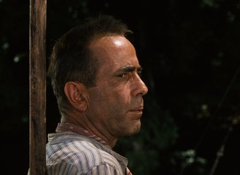 Movie still from “The African Queen” (1951), directed by John Huston – A person wearing a striped shirt near a tree; Close Up shot, Low angle