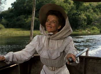 Movie still from “The African Queen” (1951), directed by John Huston – An older woman wearing a hat while standing on a boat in the water; Medium shot, Low angle