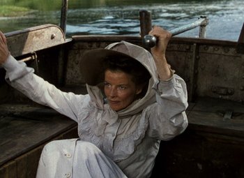 Movie still from “The African Queen” (1951), directed by John Huston – A woman sitting in a boat on the water holding a rod; Medium shot, High angle