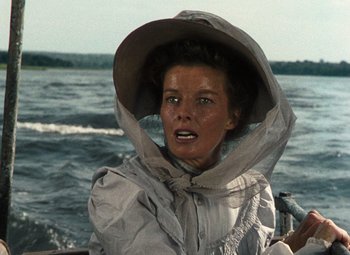Movie still from “The African Queen” (1951), directed by John Huston – A woman wearing a rain coat and hat on a boat; Close Up shot, Low angle