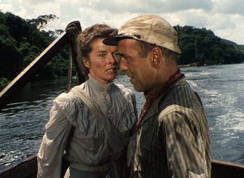 Movie still from “The African Queen” (1951), directed by John Huston – An older man and a younger woman on a boat; Medium shot, Low angle