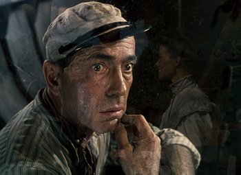 Movie still from “The African Queen” (1951), directed by John Huston – A man with a hat on and his hand under his chin; Close Up shot, Over the shoulder angle