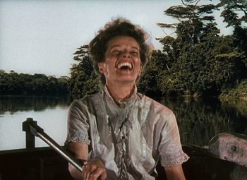 Movie still from “The African Queen” (1951), directed by John Huston – An older woman laughing while sitting in a boat; Medium shot, Low angle