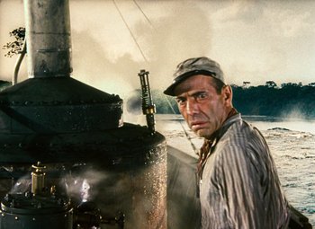 Movie still from “The African Queen” (1951), directed by John Huston – A man standing in front of an oil tank; Medium shot, Low angle