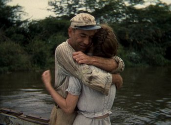 Movie still from “The African Queen” (1951), directed by John Huston – A man and a woman hugging on a dock; Medium shot, Over the shoulder angle
