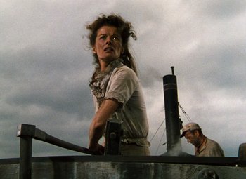 Movie still from “The African Queen” (1951), directed by John Huston – A woman standing on top of a boat in the water; Medium shot, Low angle
