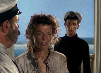 Movie still from “The African Queen” (1951), directed by John Huston – A group of people standing next to each other on a beach; Close Up shot, Over the shoulder angle