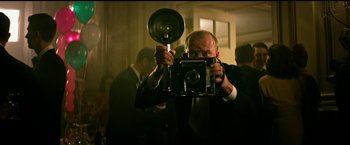 Movie still from “The Age of Adaline” (2015), directed by Lee Toland Krieger – A man taking a picture with an old fashioned camera; Medium shot, Low angle