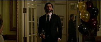 Movie still from “The Age of Adaline” (2015), directed by Lee Toland Krieger – A man in a suit and tie holding a glass of wine; Medium shot, Low angle