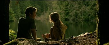 Movie still from “The Age of Adaline” (2015), directed by Lee Toland Krieger – A man and a woman sitting on the ground near a body of water; Medium shot, Over the shoulder angle