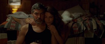 Movie still from “The American” (2010), directed by Anton Corbijn – A man and a woman sitting next to each other holding wine glasses; Medium shot, Over the shoulder angle