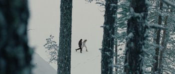 Movie still from “The American” (2010), directed by Anton Corbijn – Two people walking in the snow near a tree; Extreme Wide shot, High angle