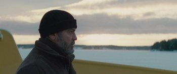 Movie still from “The American” (2010), directed by Anton Corbijn – A man with a beard wearing a black hat; Close Up shot, Low angle