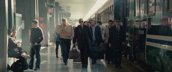 Movie still from “The American” (2010), directed by Anton Corbijn – A group of people walking down a train platform; Wide shot, Low angle