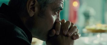 Movie still from “The American” (2010), directed by Anton Corbijn – An older man with grey hair is holding his hands to his face; Close Up shot, Low angle