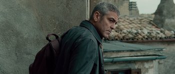 Movie still from “The American” (2010), directed by Anton Corbijn – A person with a backpack; Close Up shot, Over the shoulder angle