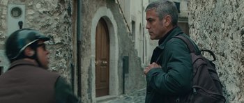 Movie still from “The American” (2010), directed by Anton Corbijn – A man standing in front of an old building; Medium shot, Over the shoulder angle