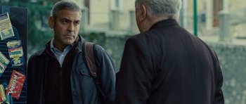 Movie still from “The American” (2010), directed by Anton Corbijn – Two older men standing next to each other on a street; Close Up shot, Over the shoulder angle