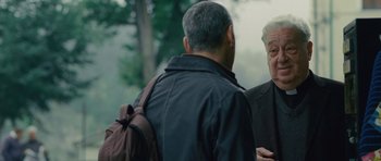 Movie still from “The American” (2010), directed by Anton Corbijn – Two older men standing next to each other in a park; Medium shot, Over the shoulder angle