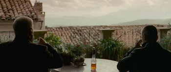 Movie still from “The American” (2010), directed by Anton Corbijn – A bottle of beer on the table; Medium shot, Over the shoulder angle