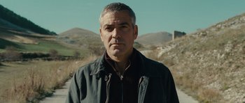 Movie still from “The American” (2010), directed by Anton Corbijn – A person wearing a jacket near some mountains; Close Up shot, Low angle