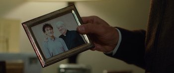 Movie still from “The American” (2010), directed by Anton Corbijn – A man holding a picture of a man and a woman; Close Up shot, Over the shoulder angle