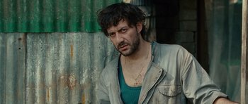 Movie still from “The American” (2010), directed by Anton Corbijn – A person wearing a jacket; Close Up shot, Over the shoulder angle