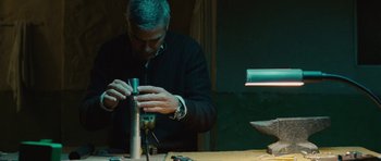 Movie still from “The American” (2010), directed by Anton Corbijn – A man working on an object on a table; Close Up shot, Low angle