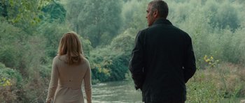 Movie still from “The American” (2010), directed by Anton Corbijn – A man and a woman standing next to a body of water; Medium shot, Over the shoulder angle