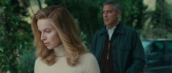 Movie still from “The American” (2010), directed by Anton Corbijn – A man and a woman standing next to each other in a forest; Close Up shot, Over the shoulder angle