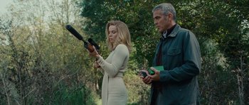 Movie still from “The American” (2010), directed by Anton Corbijn – A woman and a man are holding cell phones; Medium shot, Low angle