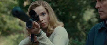 Movie still from “The American” (2010), directed by Anton Corbijn – A woman is holding a camera up to her face; Close Up shot, Low angle