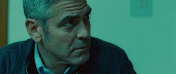 Movie still from “The American” (2010), directed by Anton Corbijn – A man's face in a green room; Close Up shot, Low angle