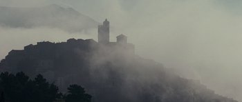 Movie still from “The American” (2010), directed by Anton Corbijn – A building on top of a hill in the middle of the fog; Extreme Wide shot, Low angle