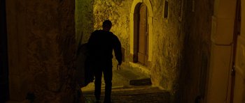 Movie still from “The American” (2010), directed by Anton Corbijn – A man walking down a street at night; Wide shot, High angle