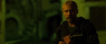 Movie still from “The American” (2010), directed by Anton Corbijn – A person holding something in his hand; Close Up shot, Low angle